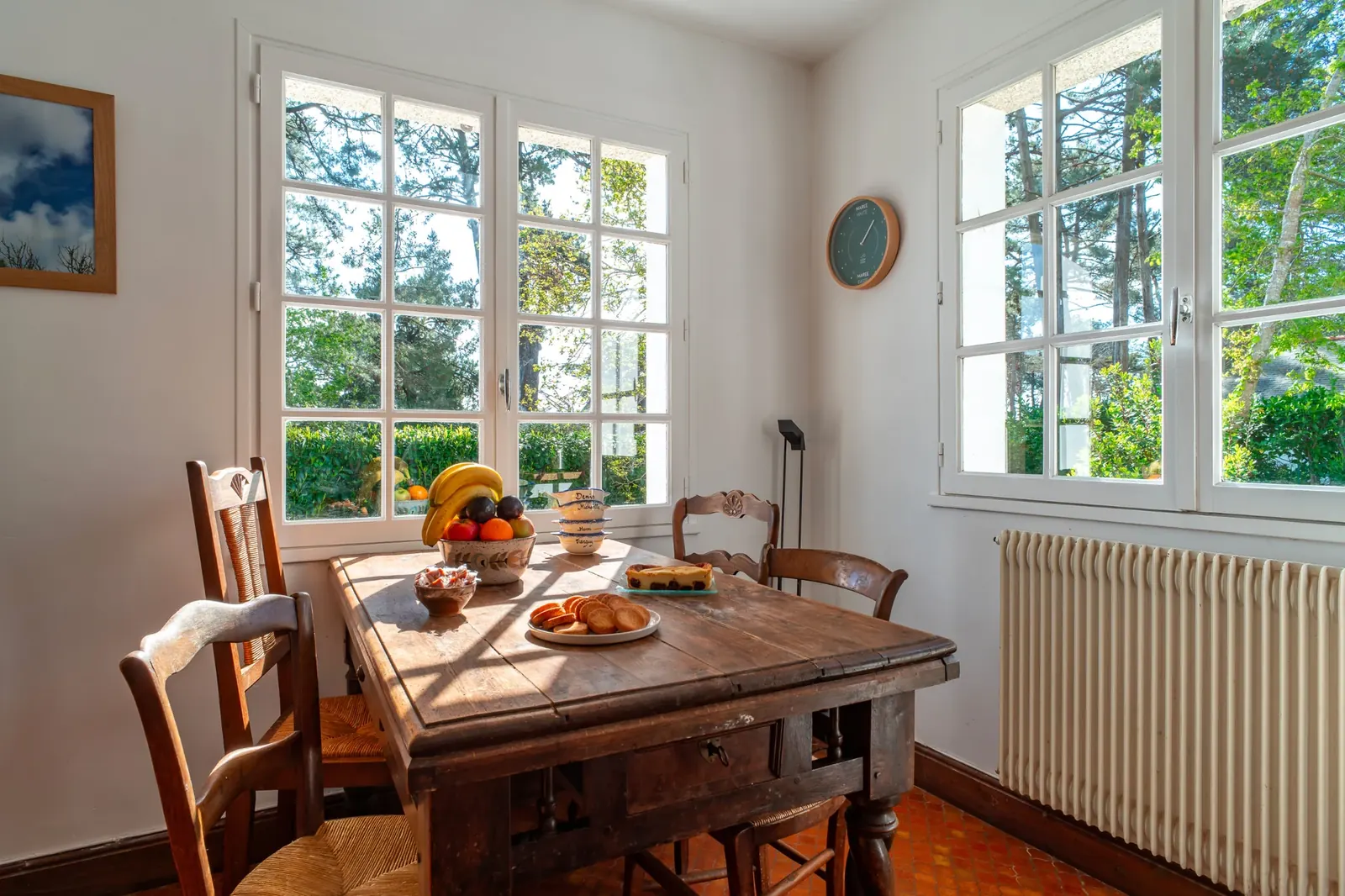 Table en bois dressée pour le petit-déjeuner devant les fenêtres
