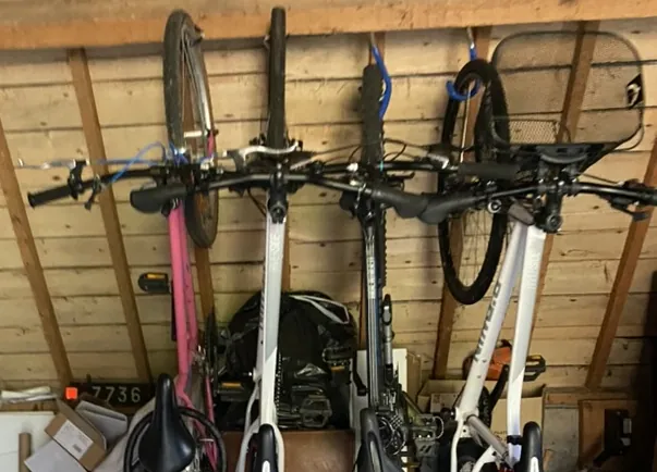 Quatre vélos suspendus, rangés dans le garage de la maison